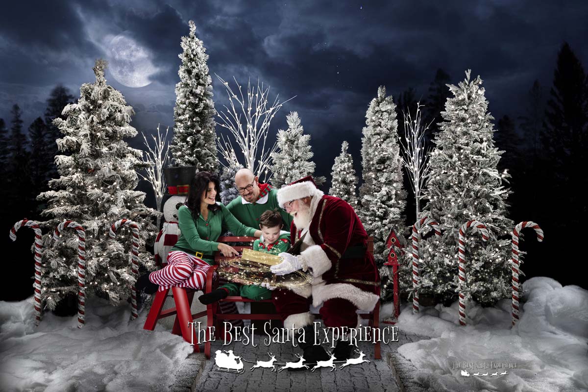 Santa reads from his Magic Book to a sweet little boy and his mom and dad in Santa's Enchanted Forest at The Best Santa Experience.